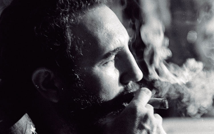 Fidel Castro Ruz de perfil fumando tabaco.