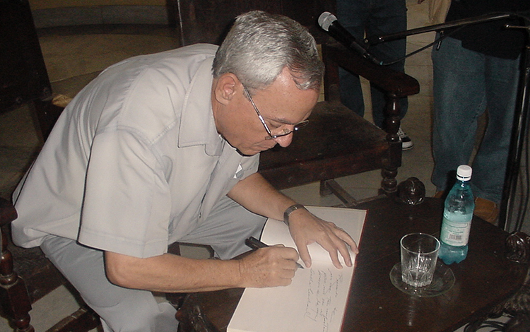 Eusebio Leal firma el libro de visitas de la Biblioteca Provincial Martí, en Santa Clara, Cuba.