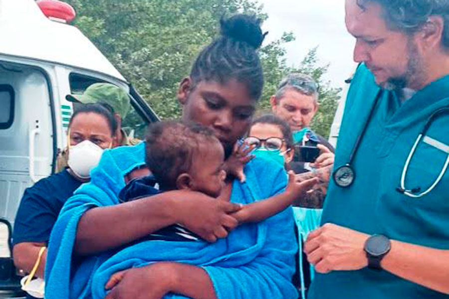 Médico atiente a madre con niño pequeño.