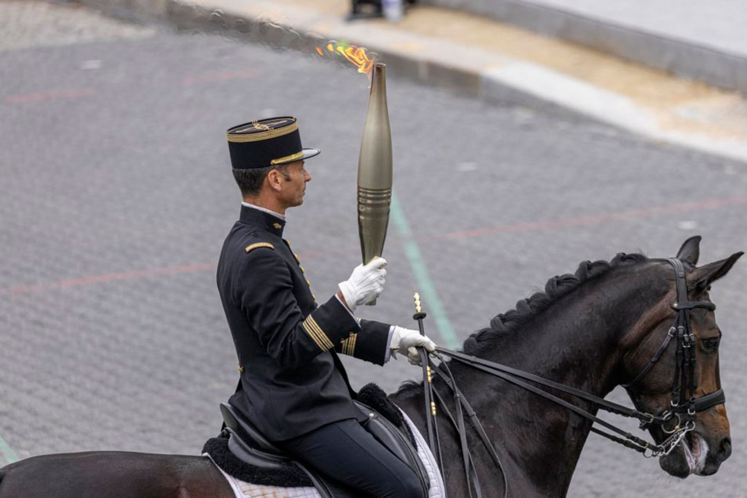 Antorcha olímpica es portada por un militar a caballo en París.