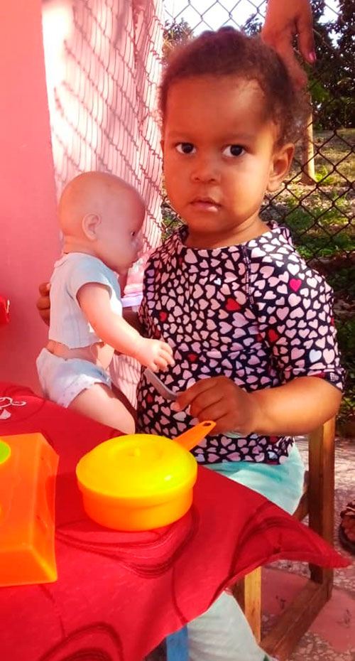 Niña jugando con una muñeca en el círculo infantil.