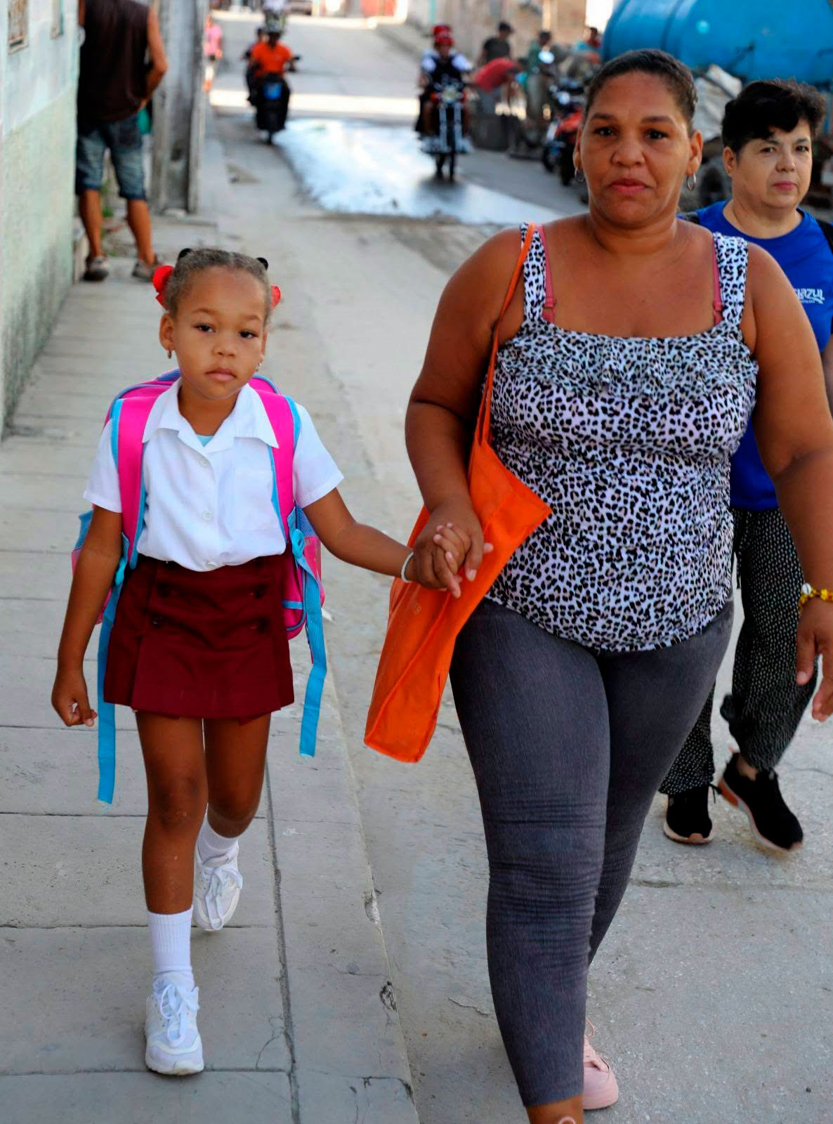 Madre e hija caminando hacia la escuela.