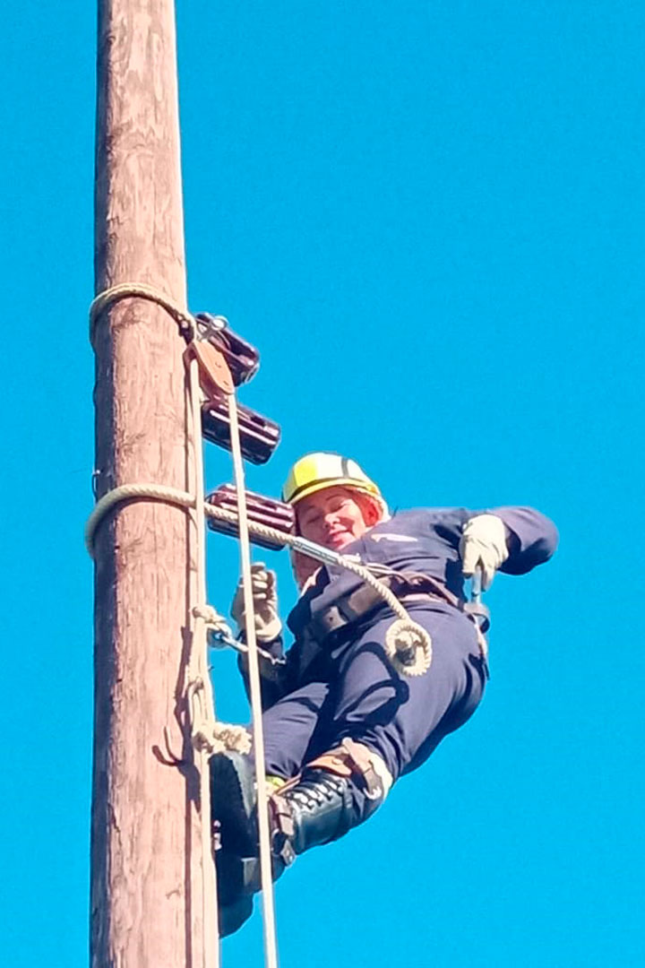 Aliuska Lores, primera liniera cubana, trabaja en las alturas de un poste eléctrico.