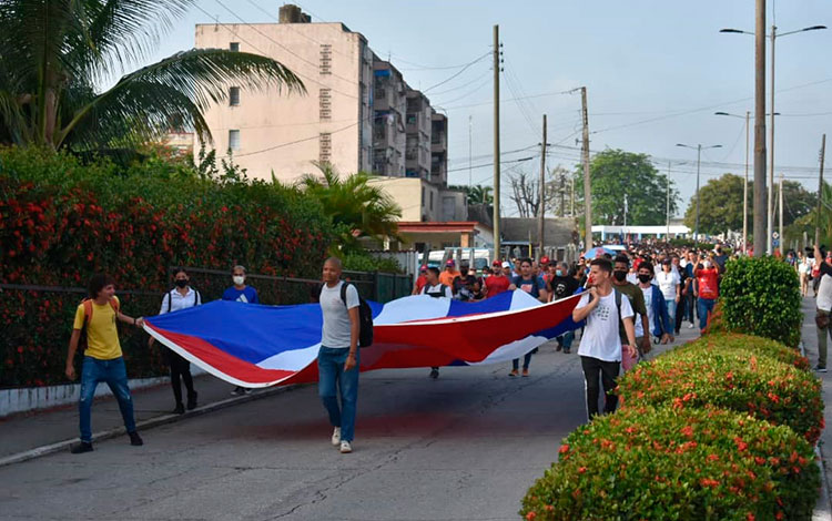 Jóvenes marchan con bandera cubana, en homenaje a Antonio Maceo y Ernesto Che Guevara.