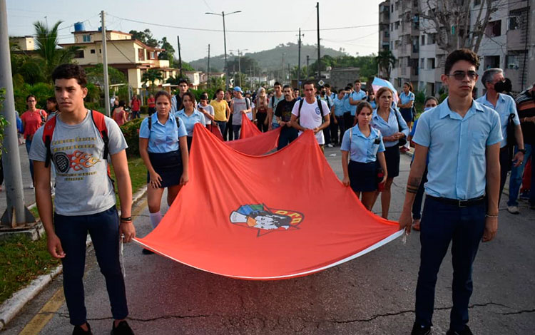 Jóvenes estudiantes marchan con bandera de la UJC en homenaje a Antonio Maceo y Ernesto Che Guevara en Santa Clara.