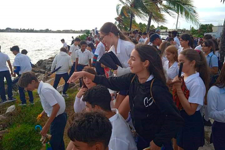 Jóvenes arrojan flores al mar en homenaje a Camilo Cienfuegos.