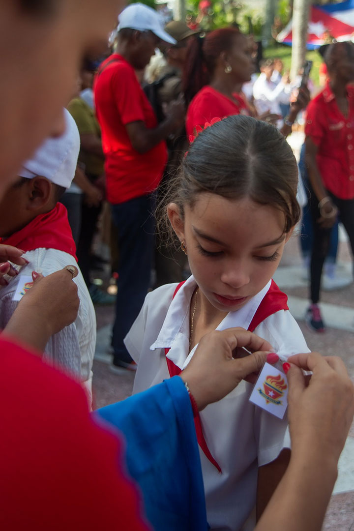 Niña recibe el distintivo de la Organización de Pioneros José Martí.