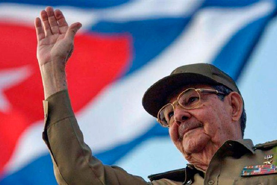 Raúl Castro Ruz saluda con la bandera cubana al fondo.