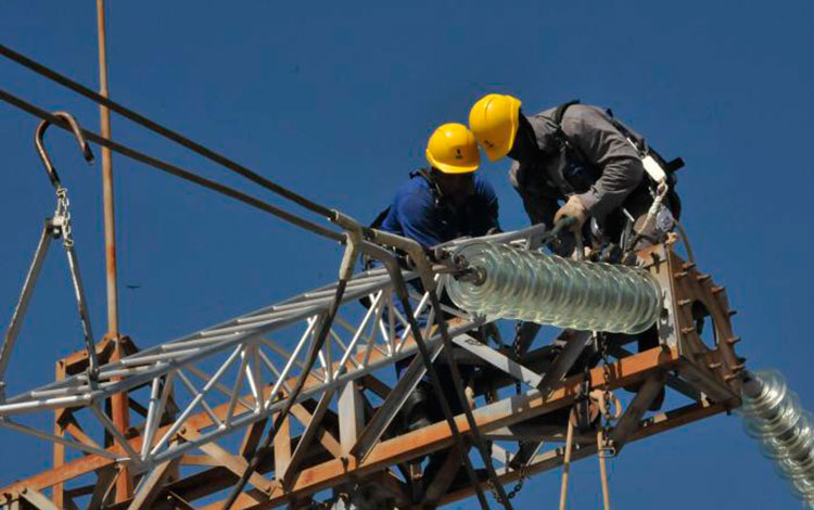 Trabajadores eléctricos laborando en una torre.