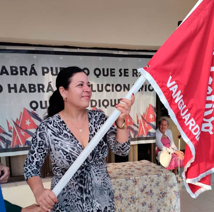 Maglin del Sol Martínez, secretaria general de la CTC en Villa Clara, entrega la bandera de Vanguardia Nacional a la sucursal bancaria.