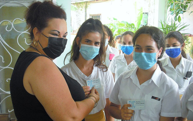 Mayelín Díaz Rodríguez, secretaria general de la FMC en Villa Clara, entrega el carné de la organización a un grupo de muchachas que inician sus vidas como federadas.