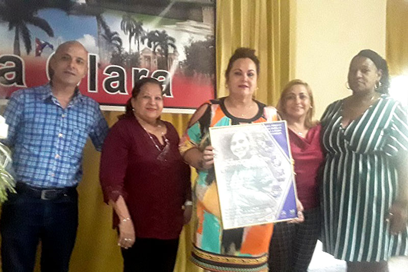 Teresa Amarelle, secretaria general FMC, y Susely Morfa, presidenta del Consejo de Defensa Provincial, entregan reconocimiento a Mayelín Díaz, secretaria saliente de la FMC en Villa Clara.