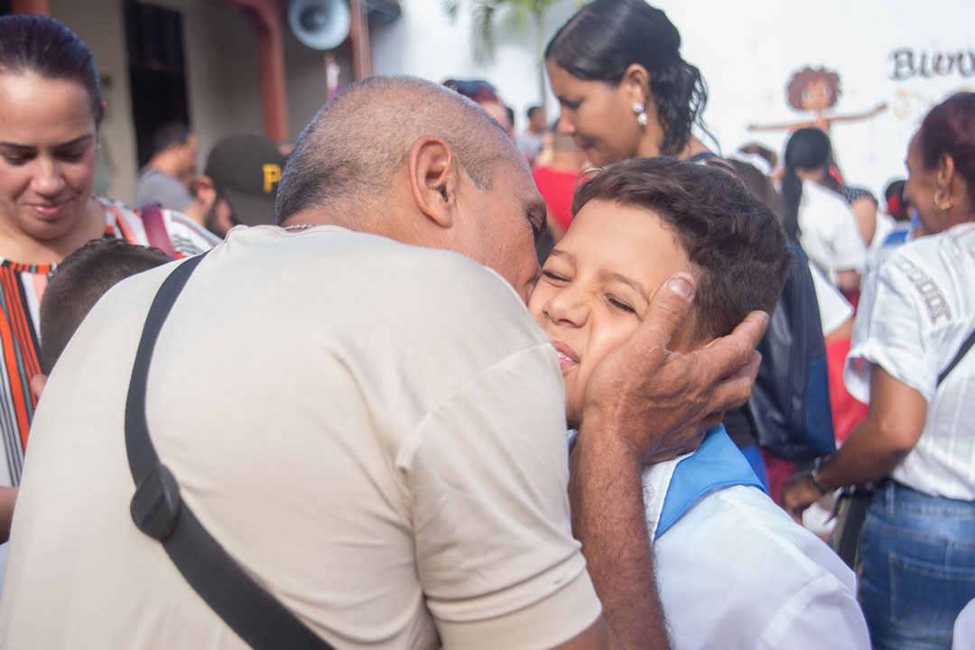 Padre besa a su hijo en el acto de cambio de atributo pioneril.