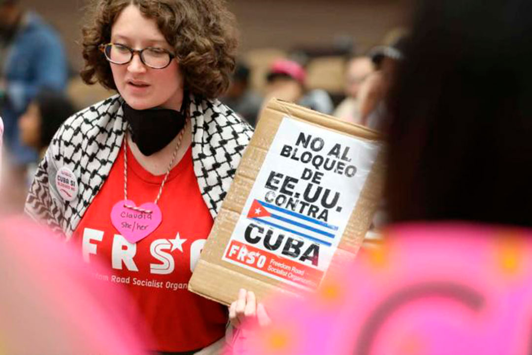 Integrante del Convoy Nuestra América con cartel de No al bloqueo de EE. UU. contra Cuba.