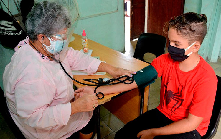 Toma de presión arterial a un adolescente antes de la vacunación anti-COVID-19.