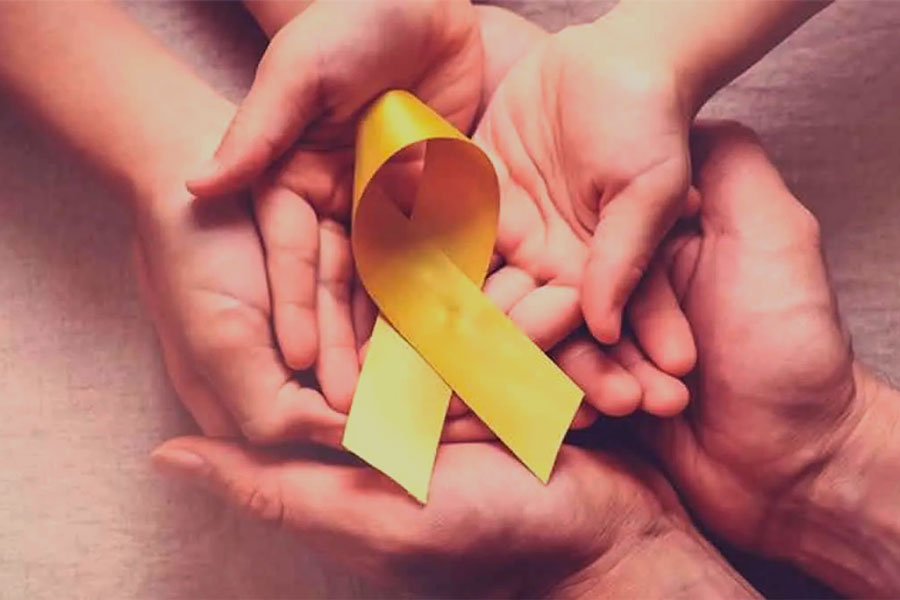 Manos y lazo amarillo del concientización del cáncer infantil.