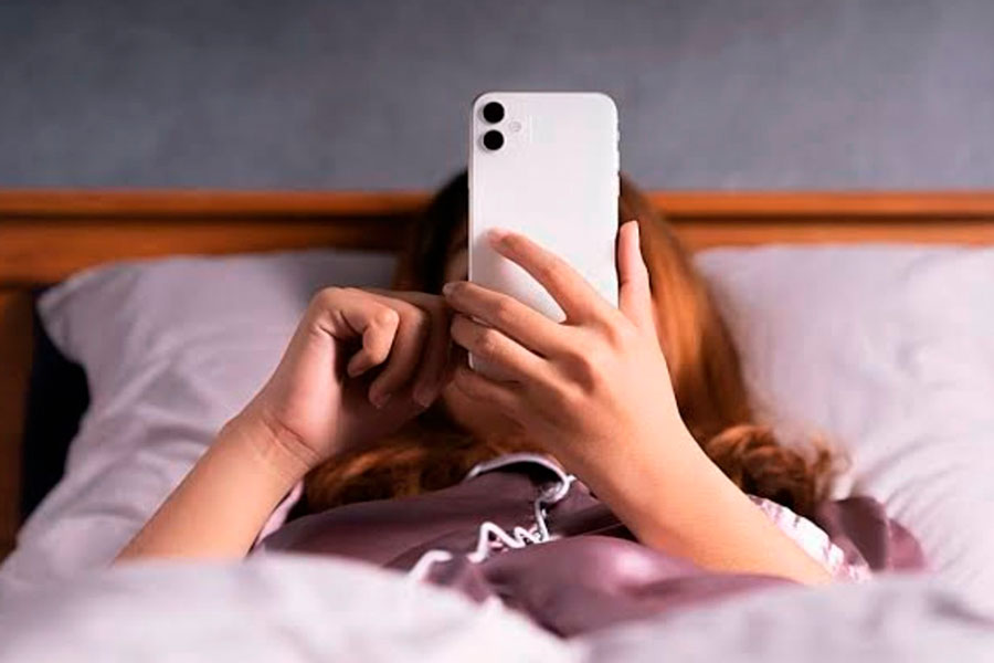 Mujer acostada con mirando el teléfono móvil.