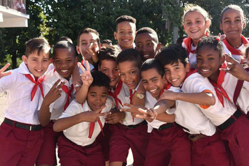 Grupo de niños cubanos con uniforme y pañoleta roja.